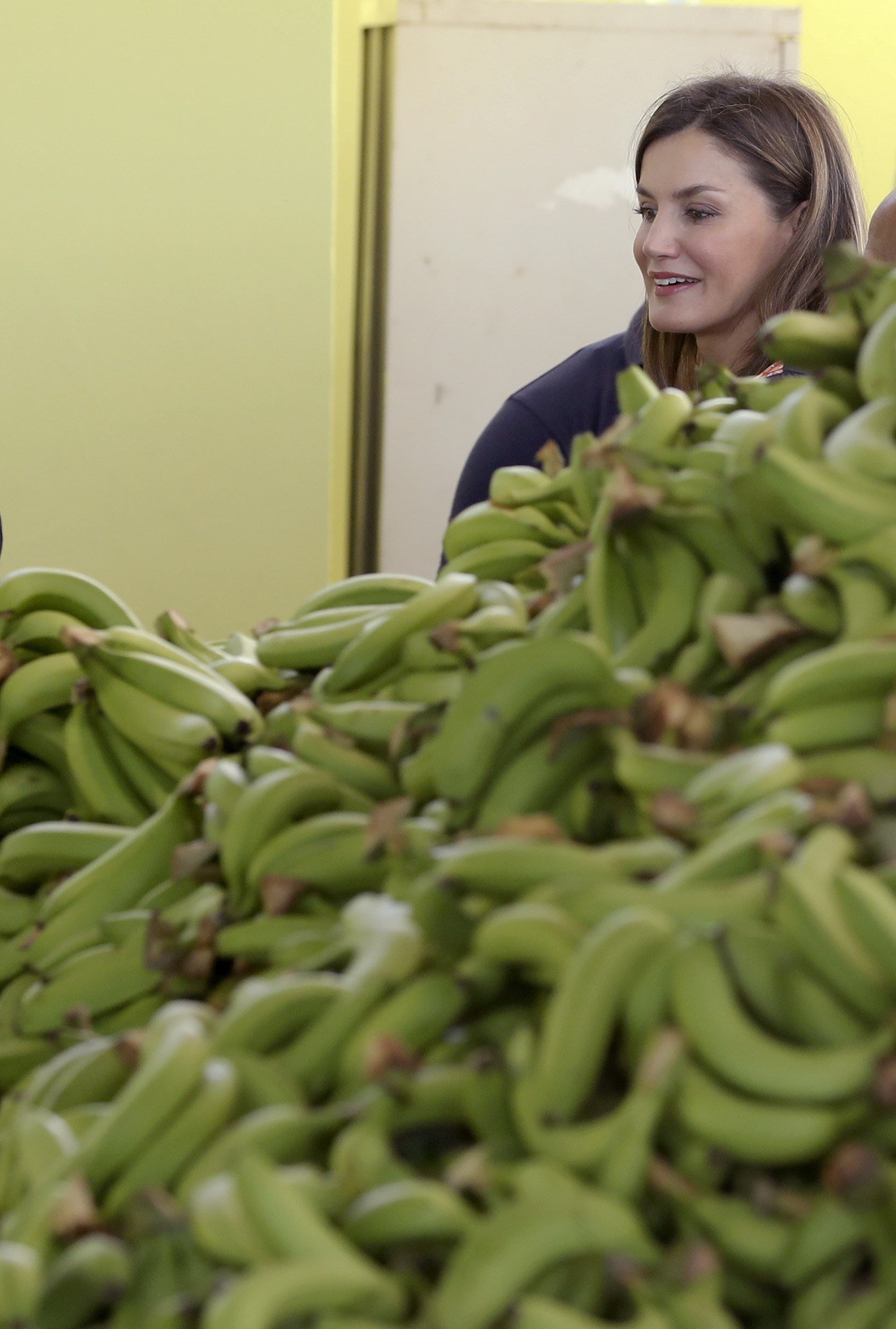 Letizia, en una plantación de plátanos con zapatos de tacón y un mono de flores