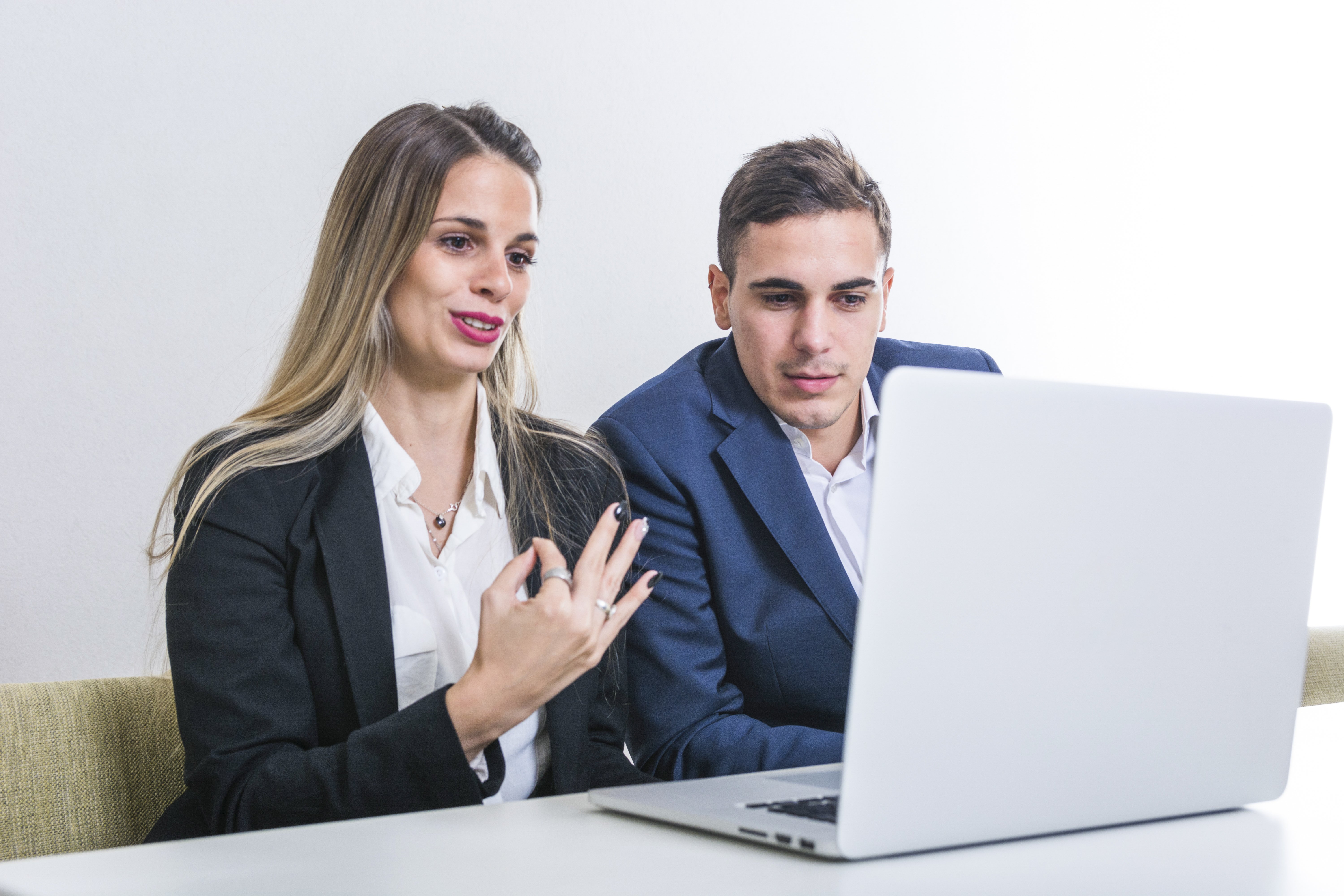 businesswoman sitting with businessman looking laptop gesturing