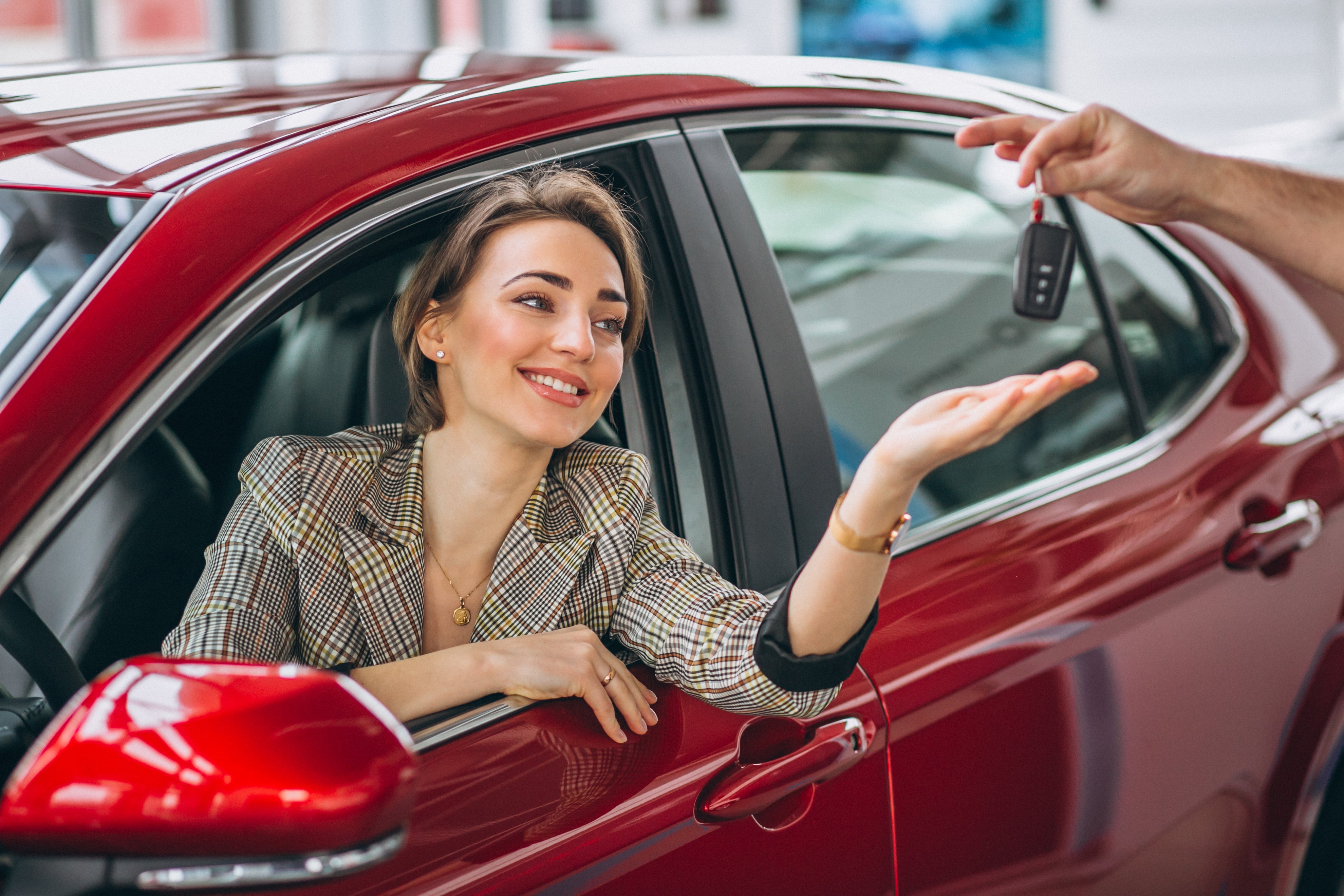 woman sitting red car receiving keys