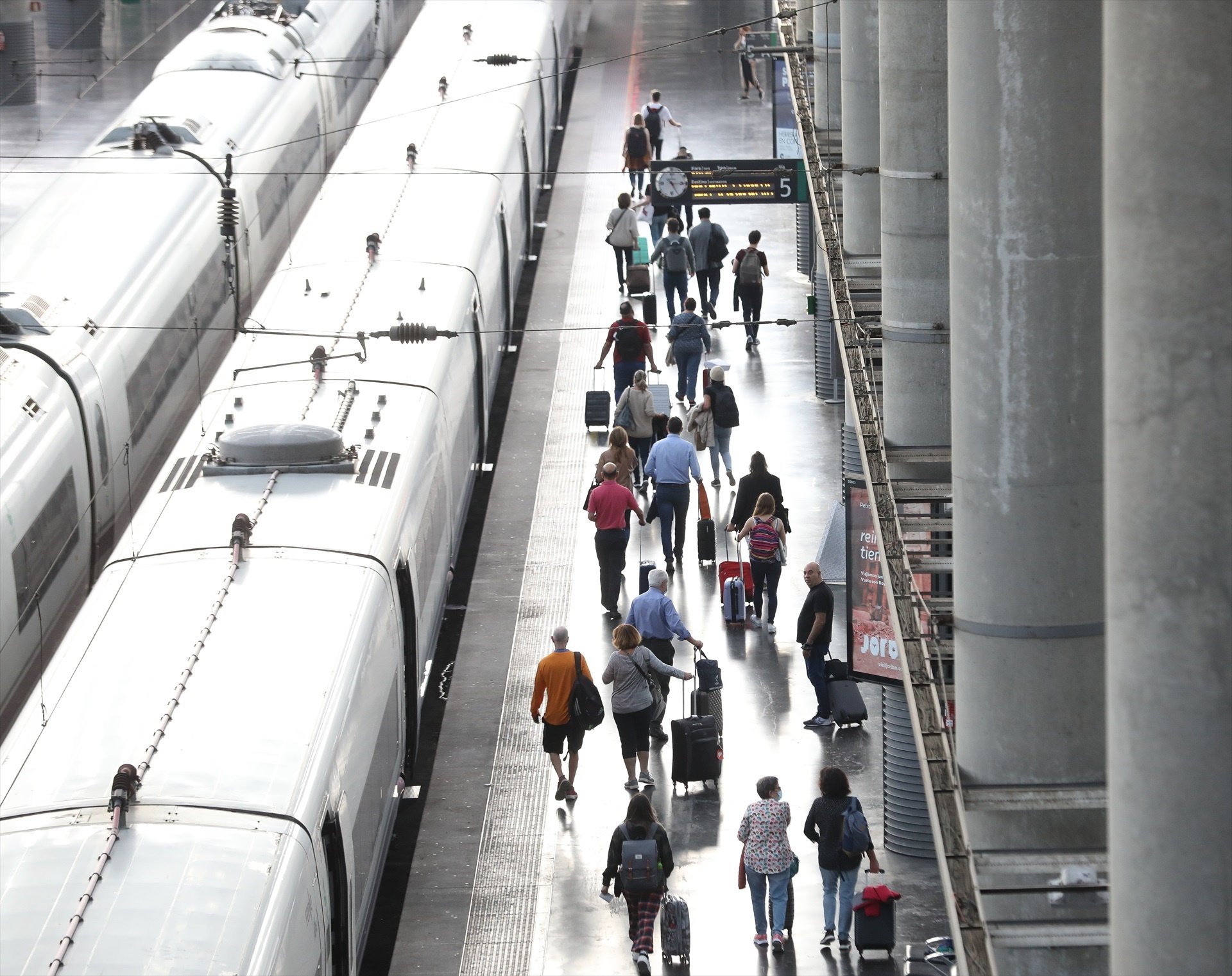 Varios pasajeros con maletas en el andén de un tren en la estación de Puerta de Atocha