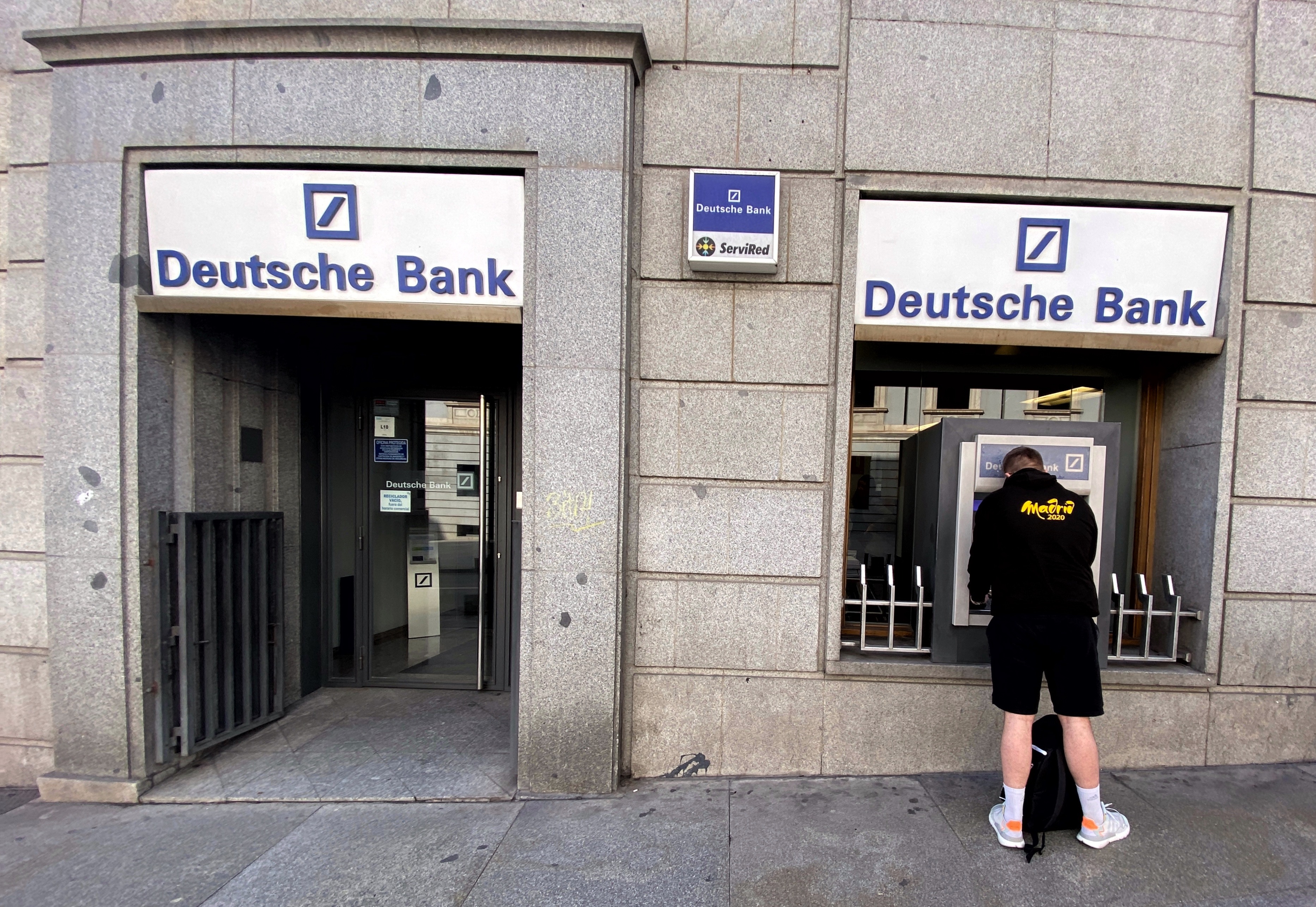Un hombre retira dinero de un cajero Deutsche Bank 