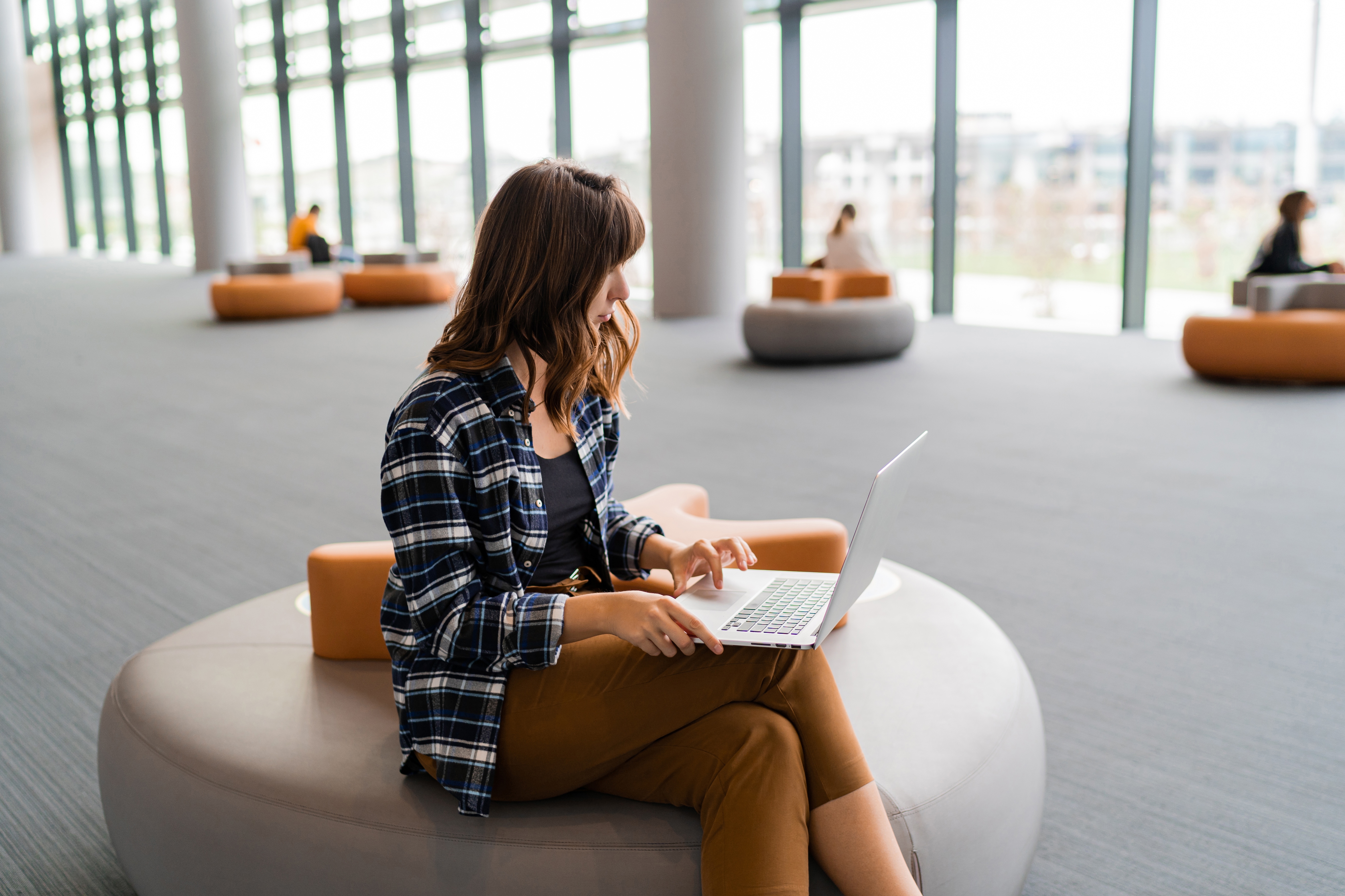 happy woman using lap top while sitting airport lounge