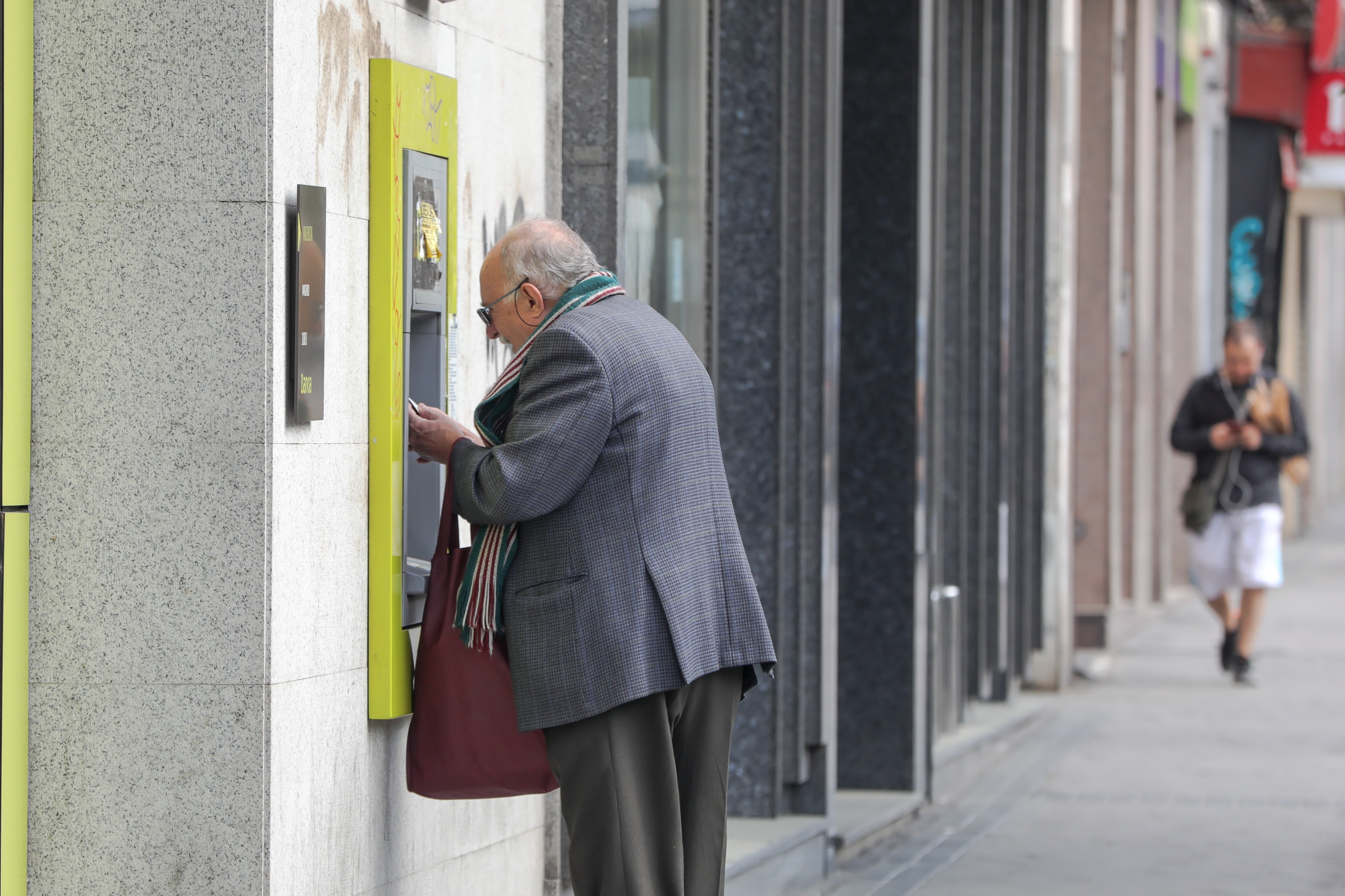 Una persona mayor retira dinero de un cajero 