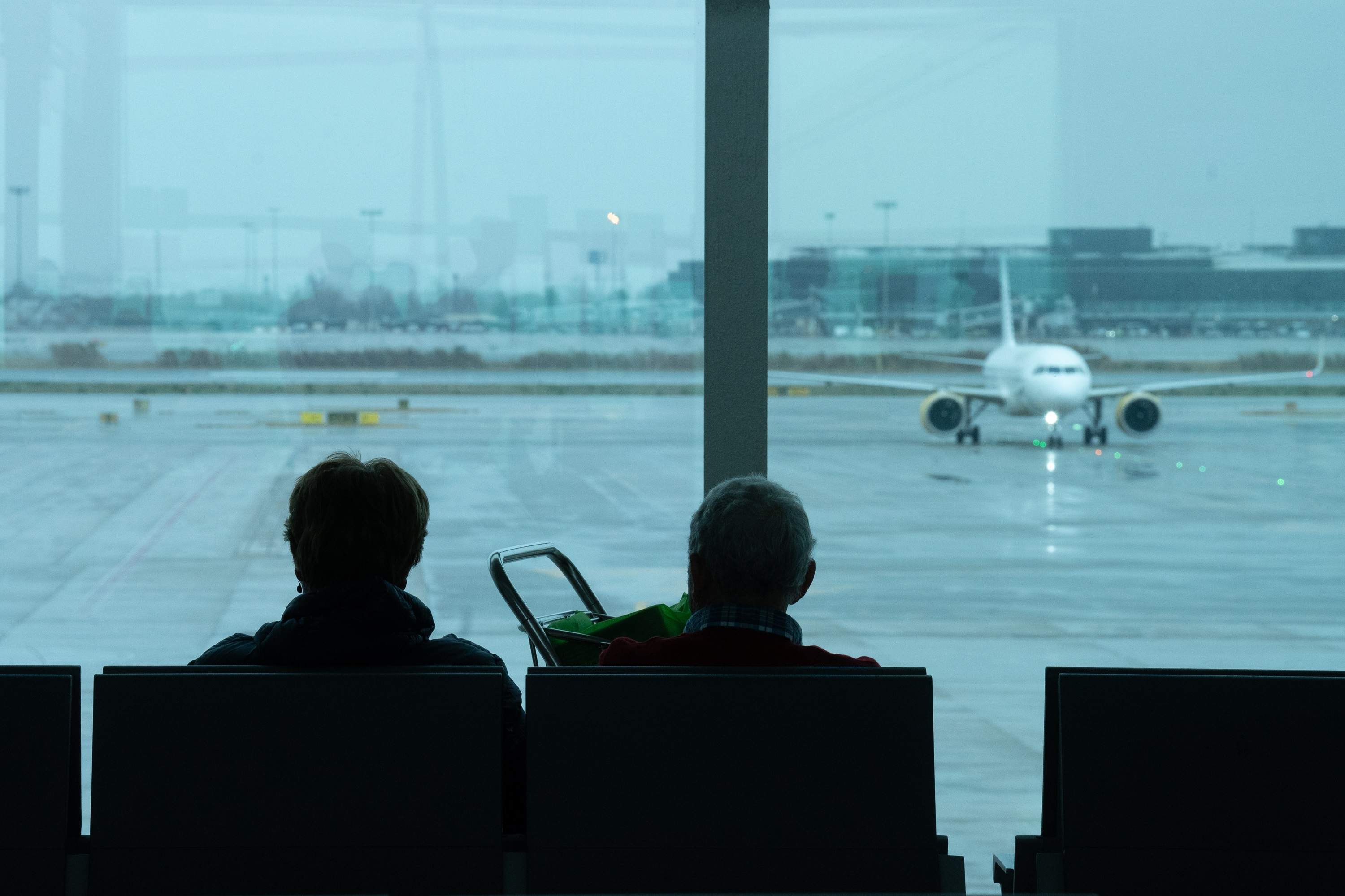 Dos personas esperan sentadas en el aeropuerto de El Prat