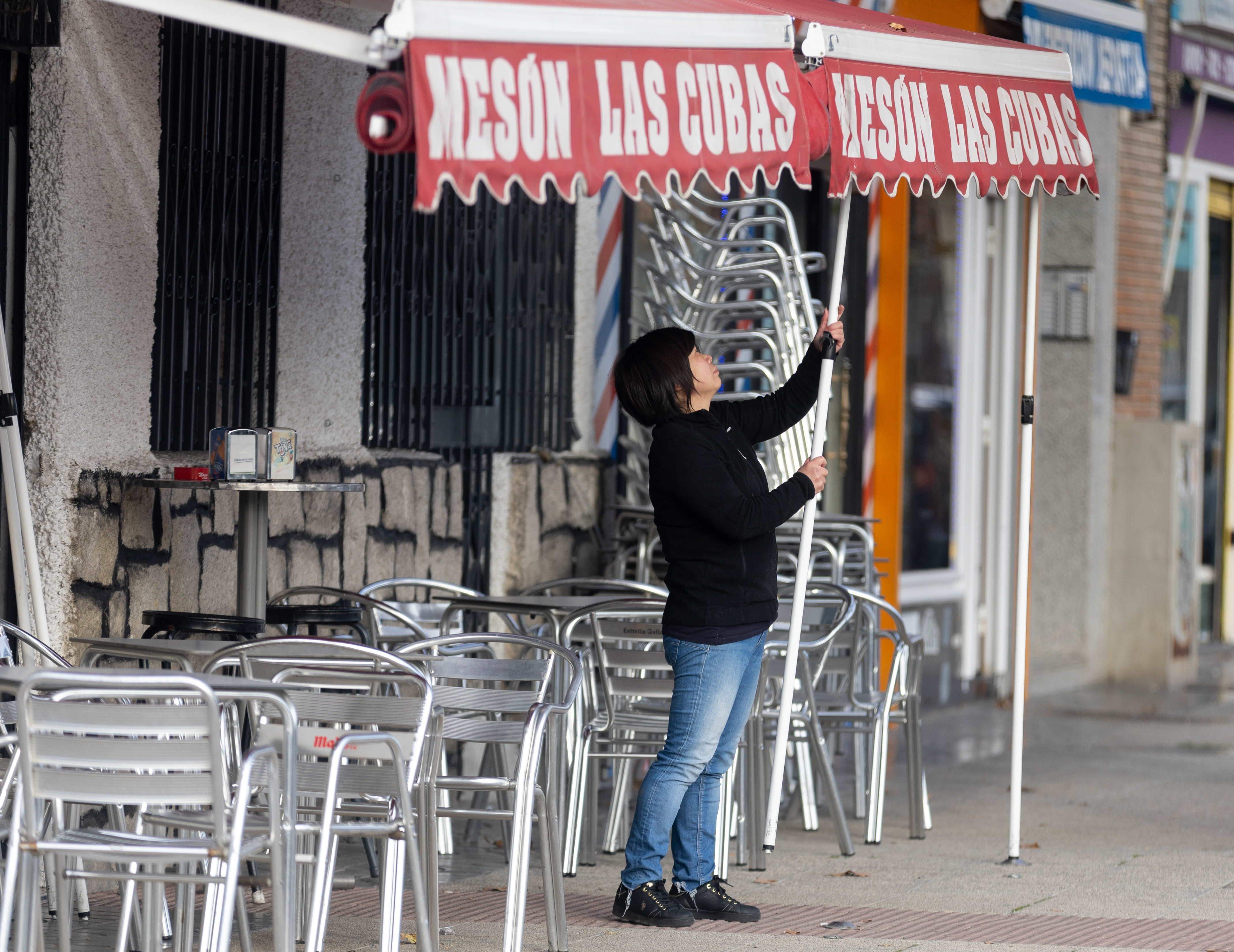 Una camarera levanta el toldo de un bar. EuropaPress