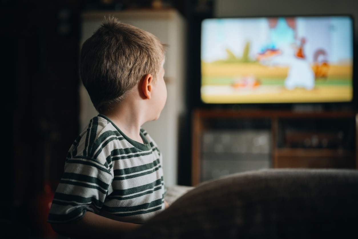 EuropaPress 6155493 rear view of cute boy sitting on sofa watching tv