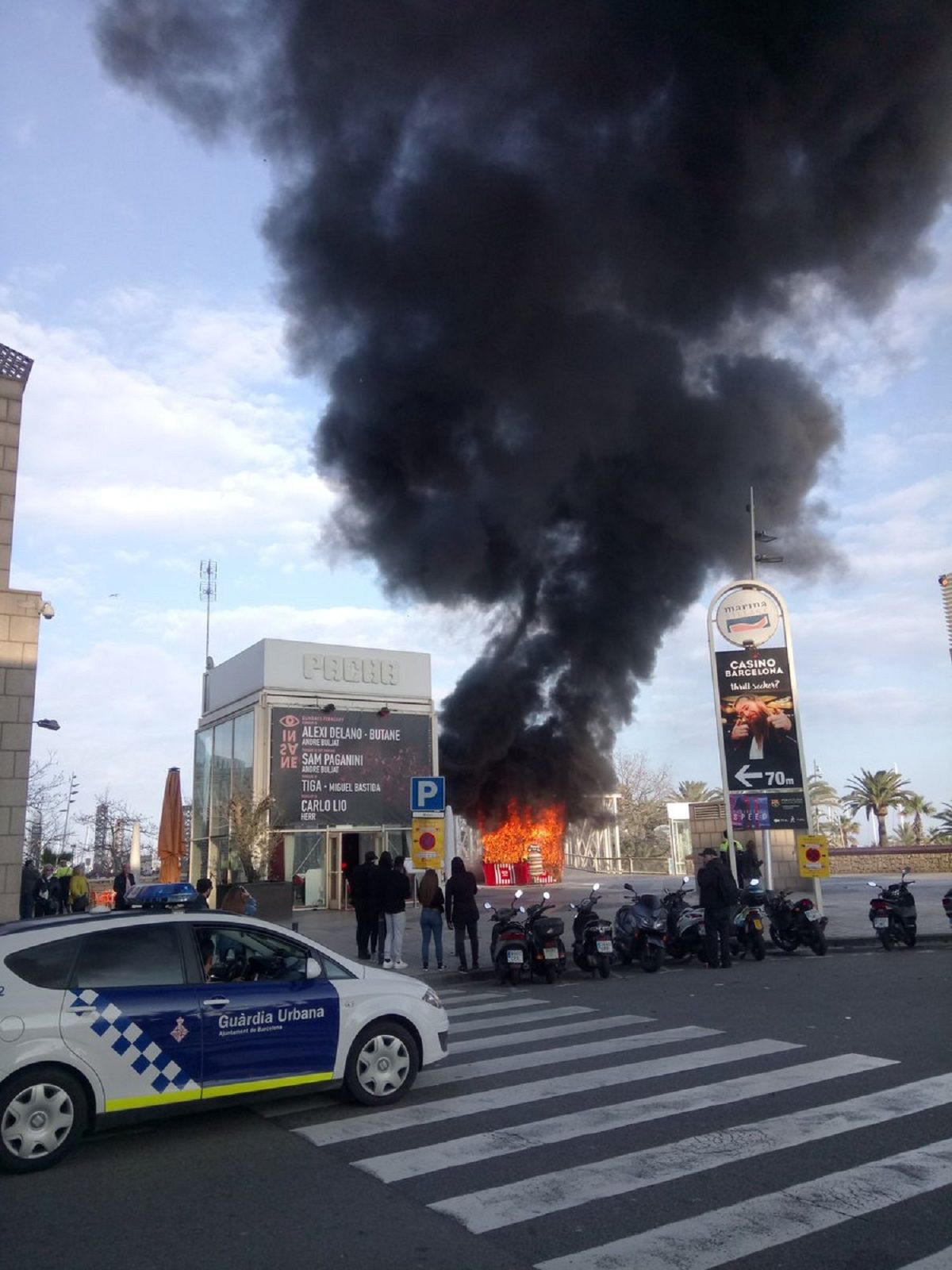Un incendio en el Port Olímpic genera una gran columna negra de humo
