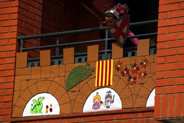 Plano contrapicado de un niño disfrazado de caballero Sant Jordi a su balcón engalanado para la Diada en Tortosa/ACN