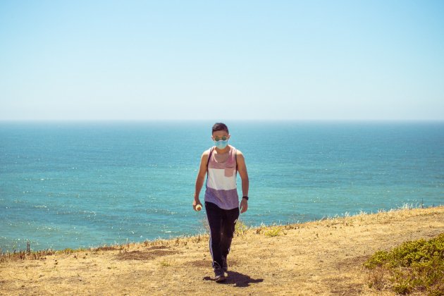 Home amb màscara a la costa