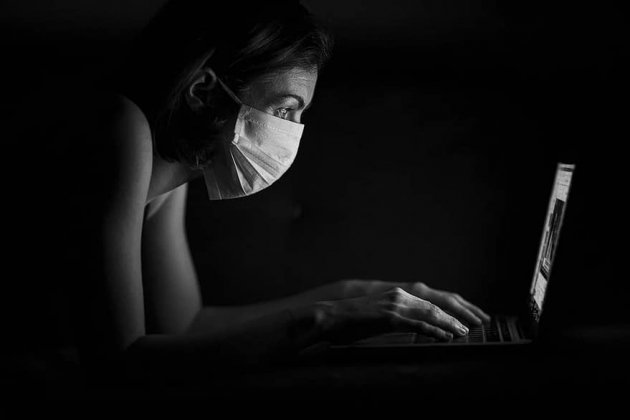 Dona amb màscara davant l'ordinador