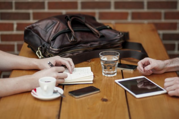 Dos usuarios trabajando en la mesa de un bar con sus dispositivos electrónicos. Foto: Pixabay