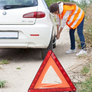 mujer arregla coche accidentado y lo señaliza triangulo / Pixabay
