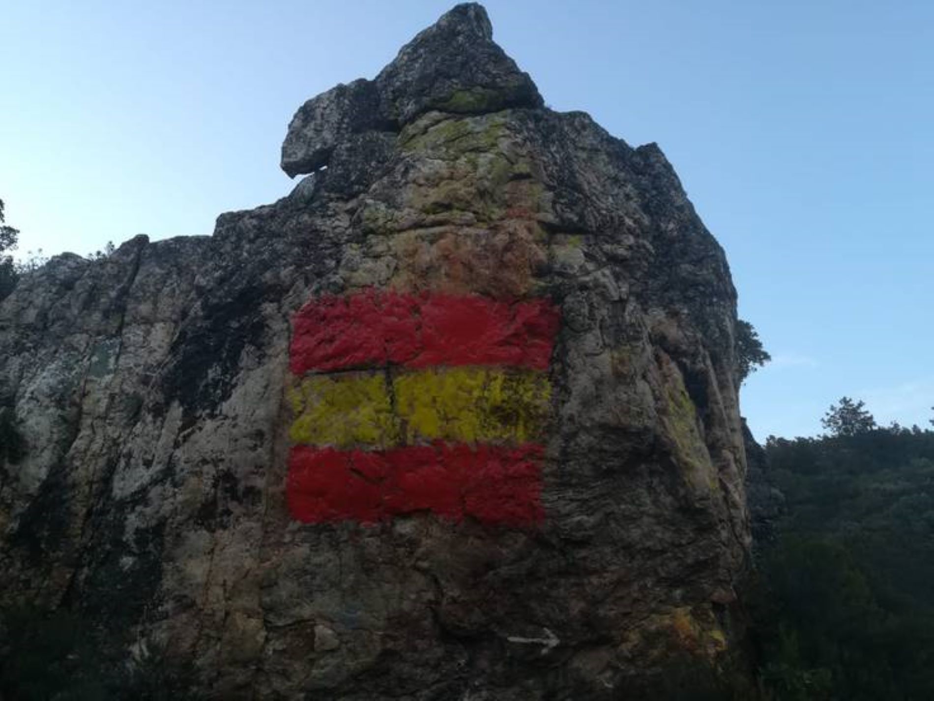 Fan malbé unes pintures rupestres pintant-hi una bandera d'Espanya a sobre