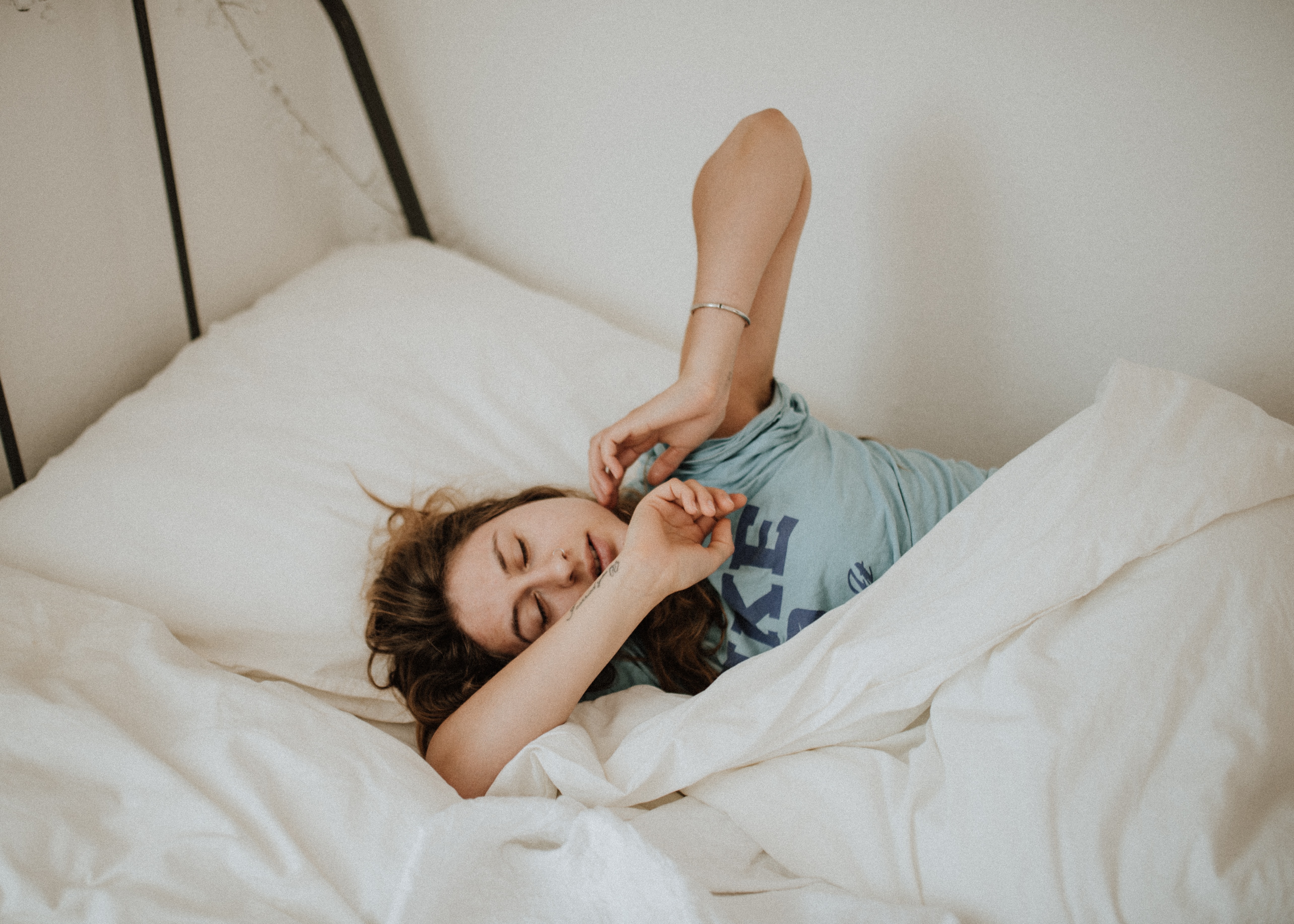 Joven estirándose en la cama : Unsplash