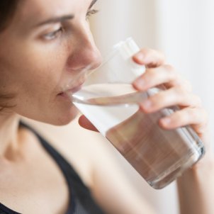 Una mujer acalorada se refresca con un vaso de agua