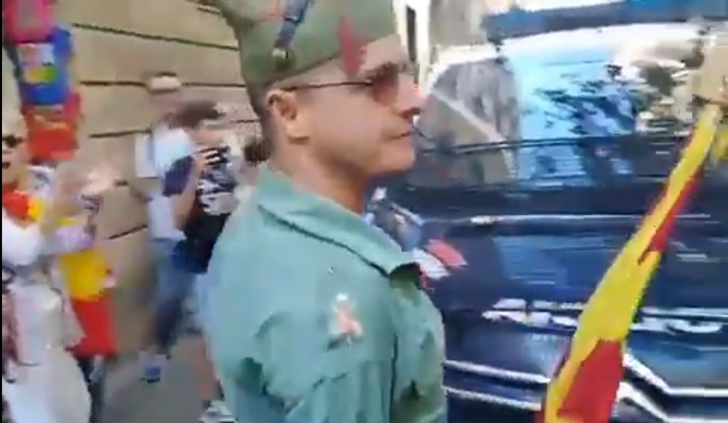 Un policía nacional se cuadra ante un manifestante disfrazado de legionario