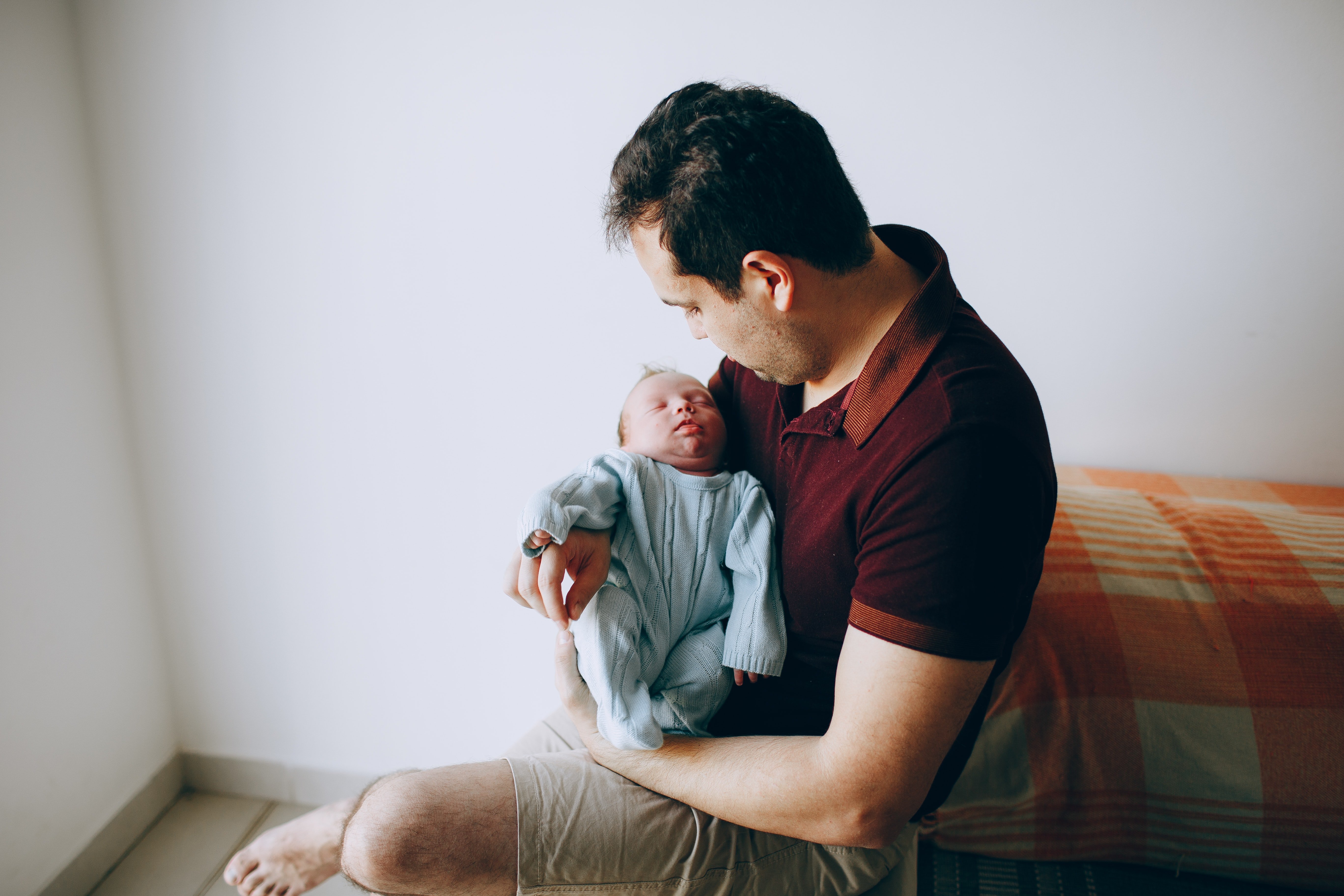 Un hombre sostiene a su hijo recién nacido / Unsplash