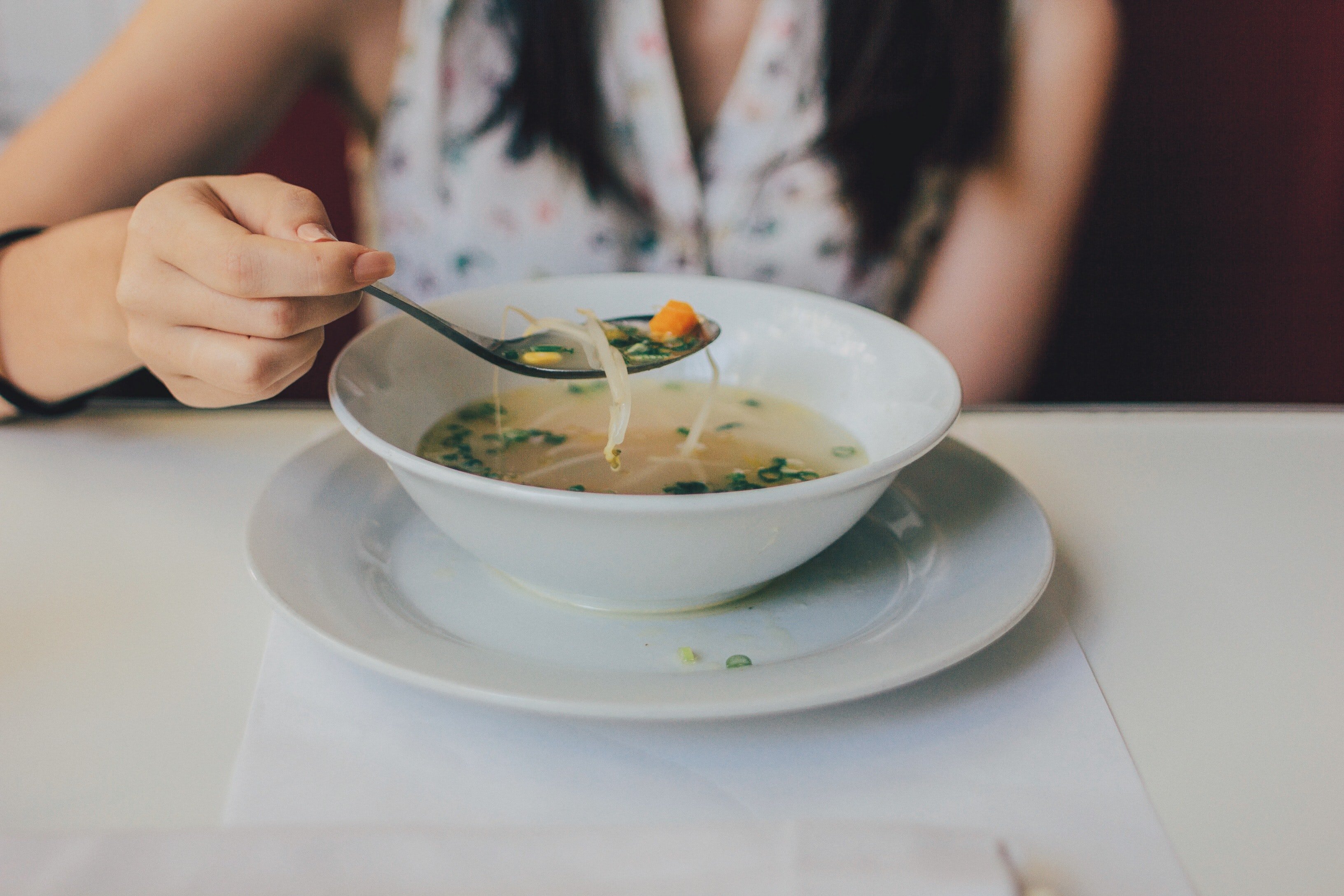 Mujer comiendo una sopa / Unsplash