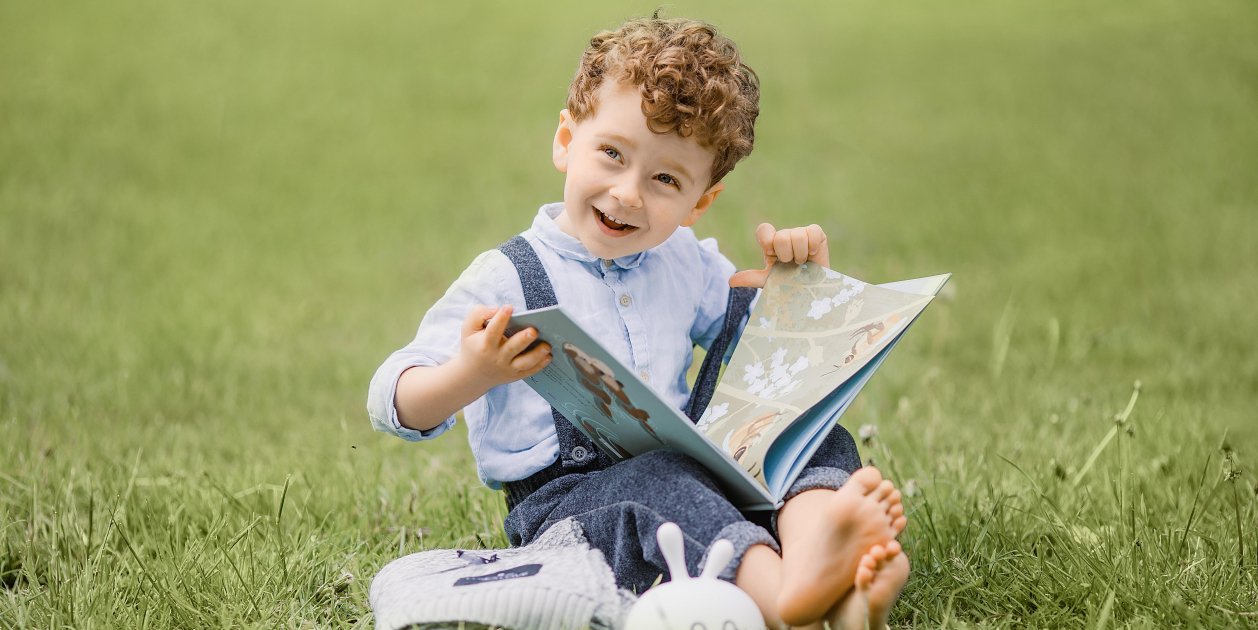 Nen amb un llibre en un jardí / Pixabay