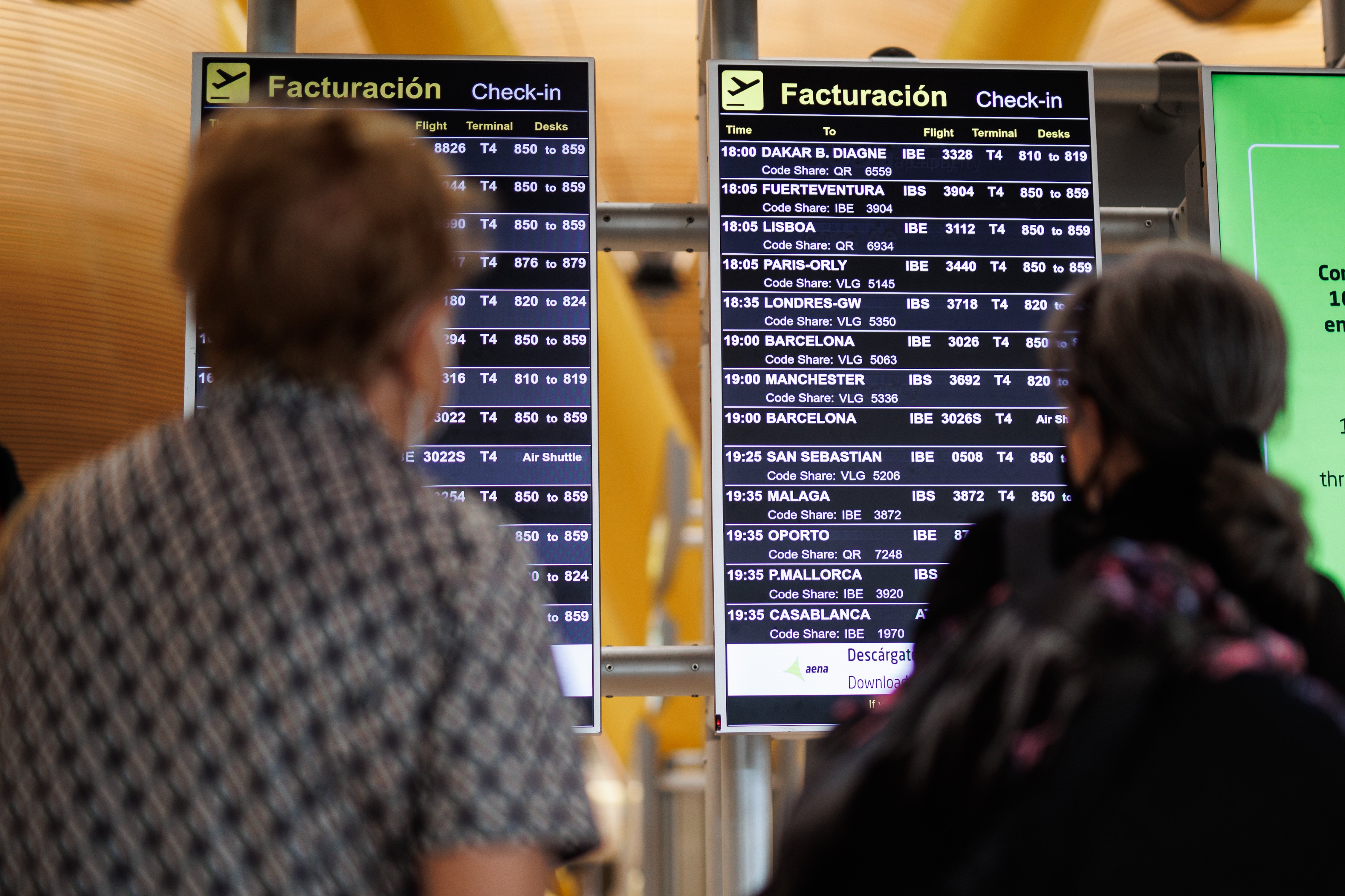 Dos personas miran un panel de información en el aeropuerto