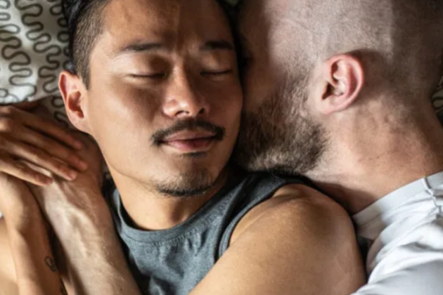 Una pareja de hombres se abrazan a la cama|lecho