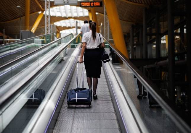 Una azafata de vuelo sube por las escaleras mecánicas Una azafata de vuelo sube por las escaleras mecánicas