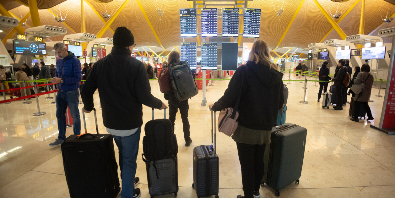 Pasajeros buscan su vuelo en un cartel del aeropuerto