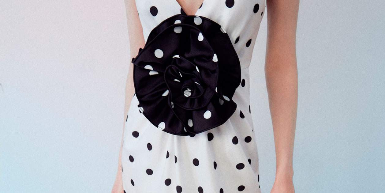 Nos hemos comprometido a amar el vestido de lunares de Sfera con una flor XL en escote