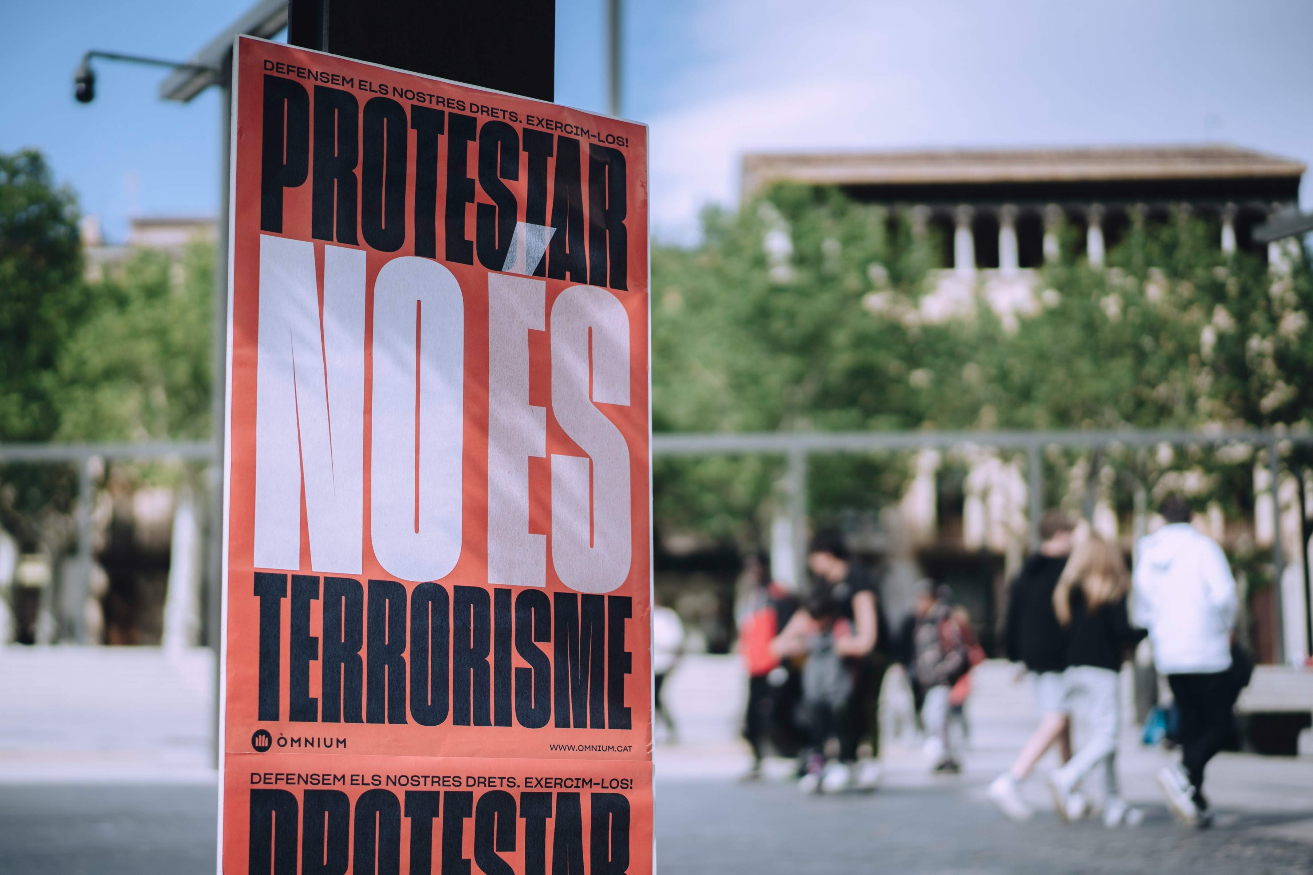 Òmnium entra en campaña con una pegada de carteles con el lema "Protestar no es terrorismo"