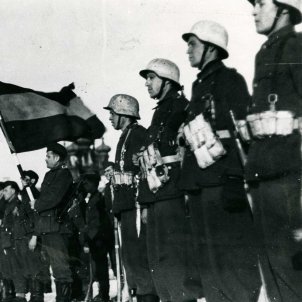 Fotografía de la bandera española presidiendo un acto de la División Azul