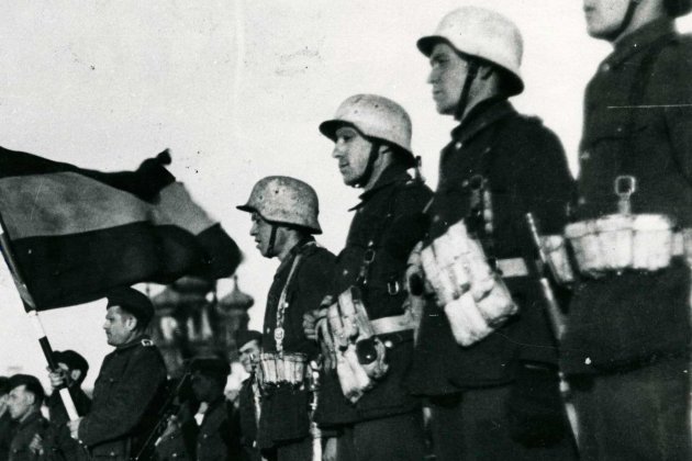 Fotografía de la bandera española presidiendo un acto de la División Azul