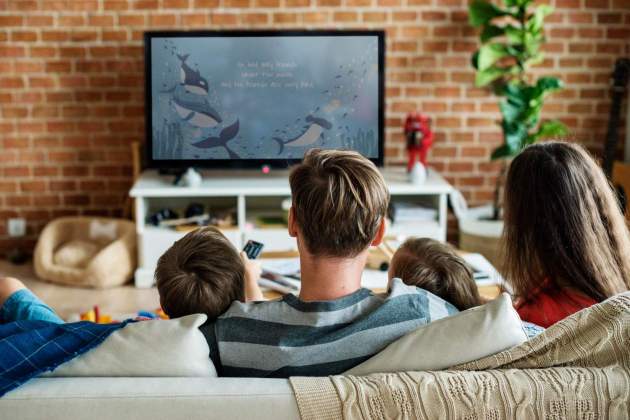 Personas viendo la televisión en el sofá de casa