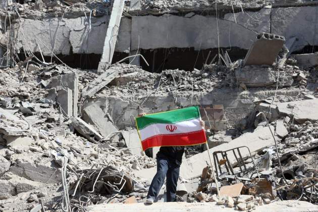 Un iraní coloca la bandera nacional de Irán entre las ruinas de una comisaría de policía dañada en el centro de Teherán, Irán Efe