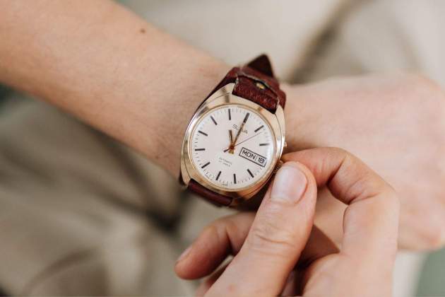 Imatge d'una persona canviant l'hora del rellotge Imatge d'una persona canviant l'hora del rellotge