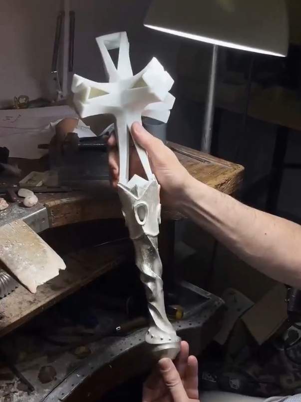 La creu està feta de porcellana sintètica blanca i representa la llum i la puressa, i la base és de plata, i representa els núvols angelicals de la Façana del Naixement La creu està feta de porcellana sintètica blanca i representa la llum i la puressa, i la base és de plata, i representa els núvols angelicals de la Façana del Naixement