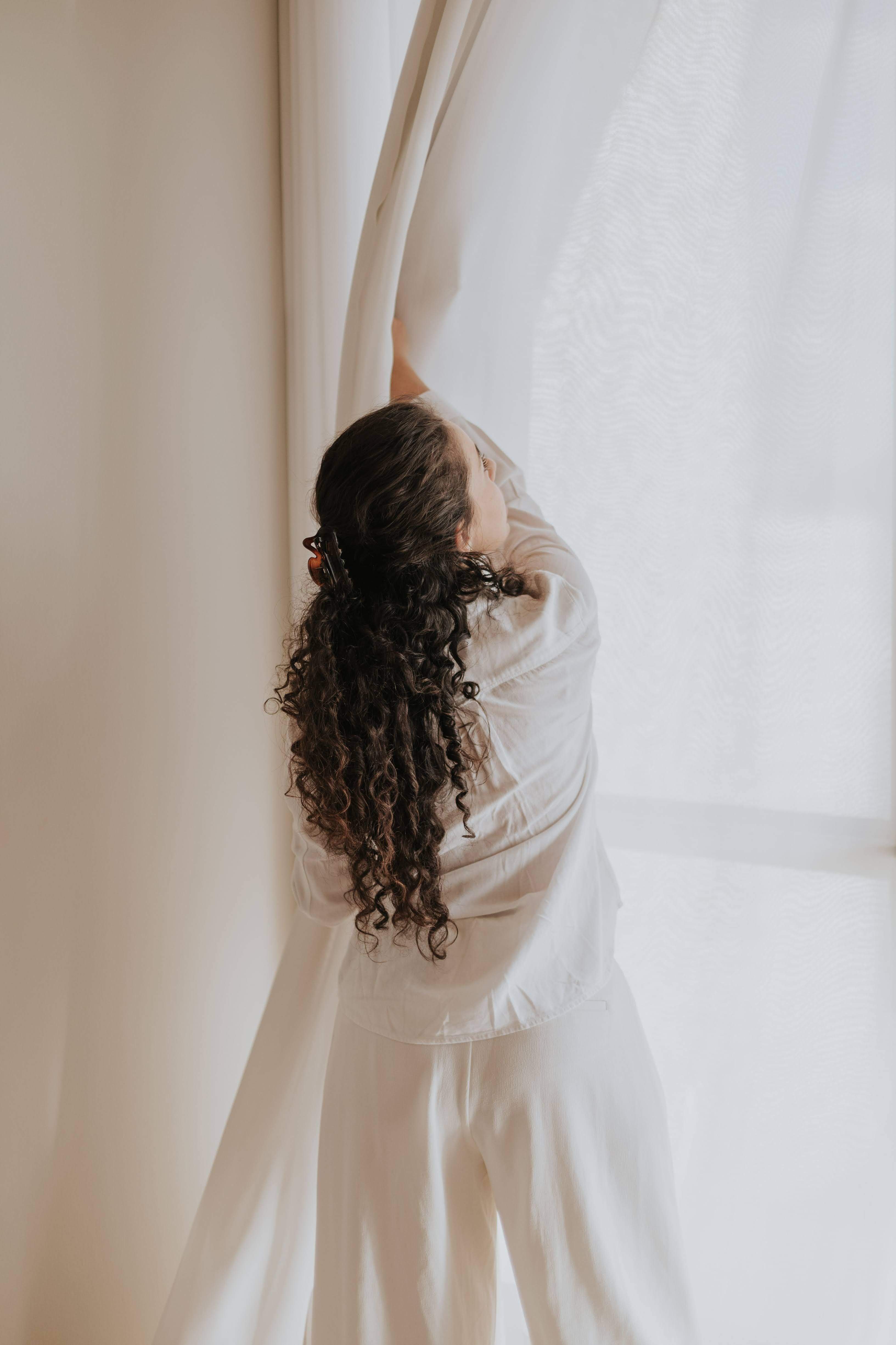 Imatge d'arxiu d'una dona amb unes cortines / Foto: Pexels