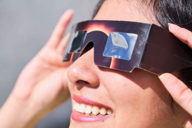 Imatge d'una dona amb ulleres per veure l'eclipsi Imatge d'una dona amb ulleres per veure l'eclipsi