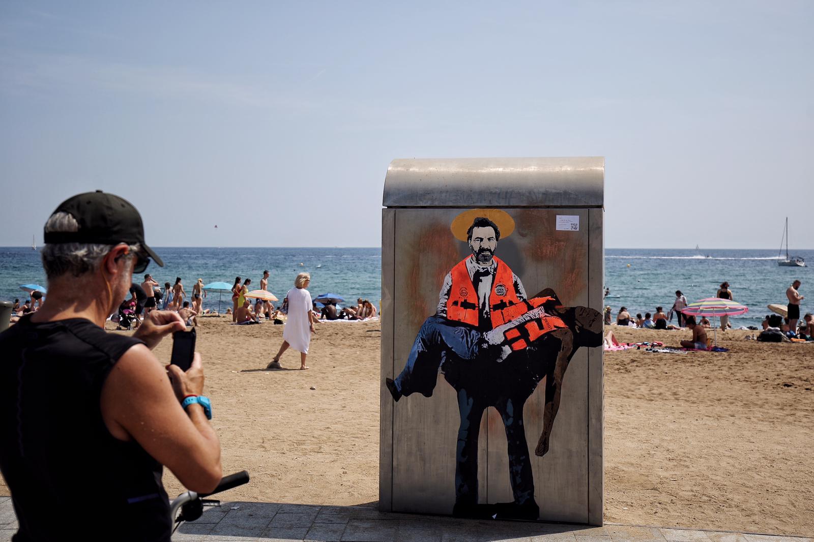 El artista Tvboy "santifica" a Òscar Camps con un migrante en los brazos en la Barceloneta