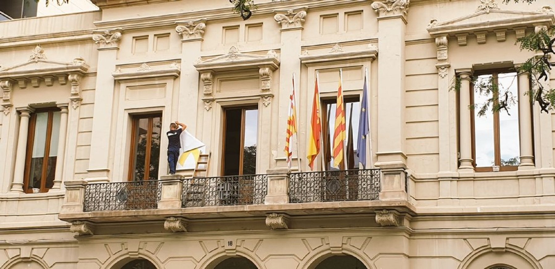 El PSC de Barcelona retira el lazo amarillo de la fachada de la sede del distrito de las Corts
