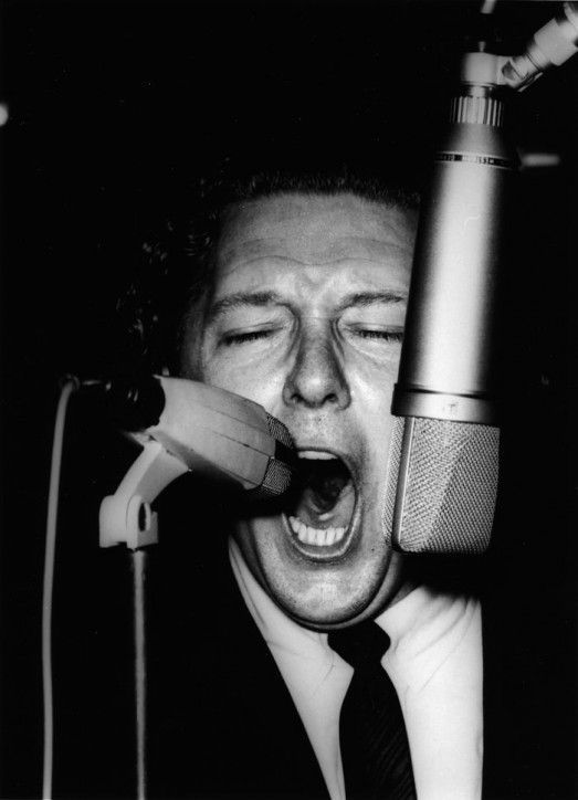 Jerry Lee Lewis performs on stage, singing into two microphones, at the Deutschlandhalle in 1963 in Berlin, Germany. (Photo by K & K Ulf Kruger OHG/Redferns)