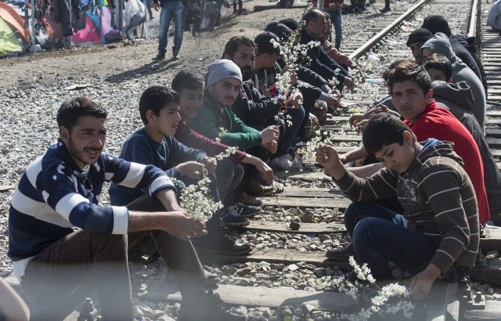 GEO25 GEVGELIJA (MACEDONIA) 01/03/2016.- Varios refugiados sostienen ramos de flores mientras esperan en la parte griega poder cruzar a Macedonia, cerca de la localidad macedonia de Gevgelija, hoy, 1 de marzo de 2016. Unos 30.000 refugiados y migrantes están atrapados en estos momentos en Grecia a la espera de poder continuar su ruta hacia el norte de Europa, mientras que la frontera con Macedonia está herméticamente cerrada tras los incidentes registrados este lunes. EFE/Georgi Licovski